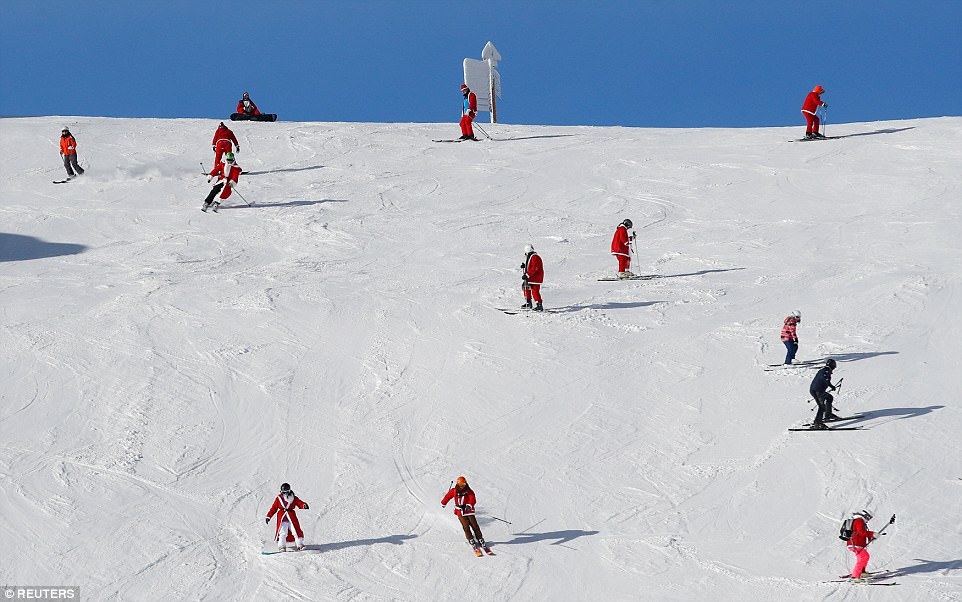 Чоловіки, жінки та діти, одягнені в червоне вбання Санти, катаються на лижах у Верб'є.
