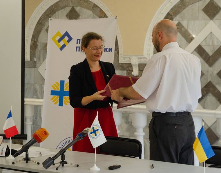 Посол Франції Ізабель Дюмон передає маріупольцям підписану грантову угоду про створення дитячої кімнати. Фото надане автором