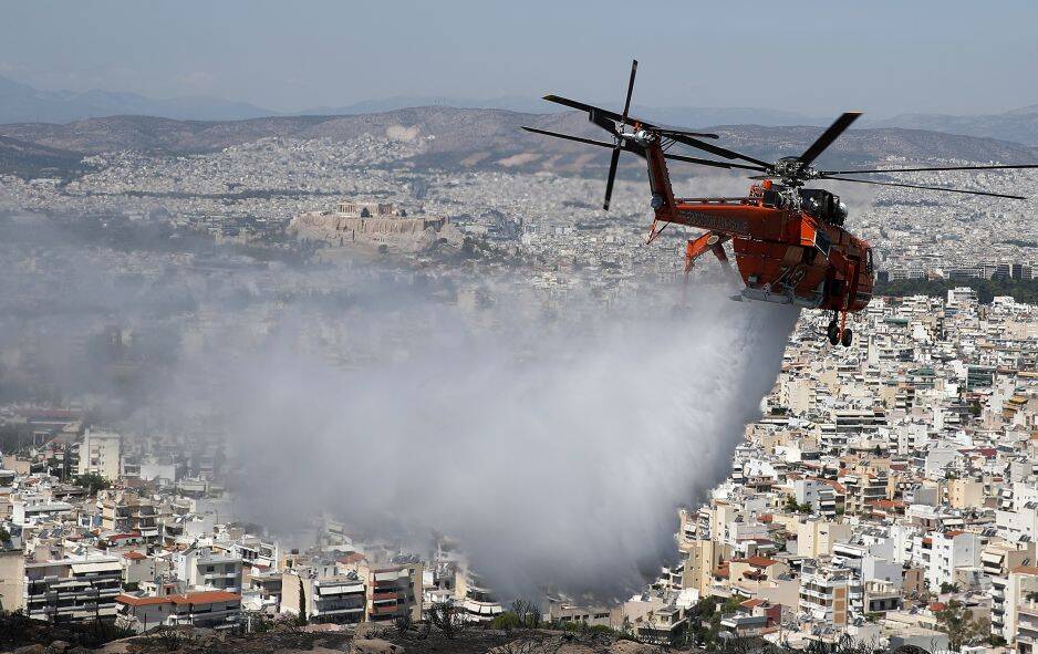 Вертоліт гасить пожежу над пагорбом у східному передмісті Афін Віронаса. Древній пагорб Акрополя видно на задньому плані фото, 28 серпня 2019 року. AP Photo 