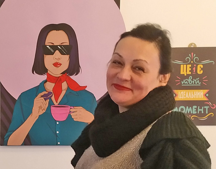 Олена Логвіненко біля полотна, яке подарувала закладові художниця-волонтерка
