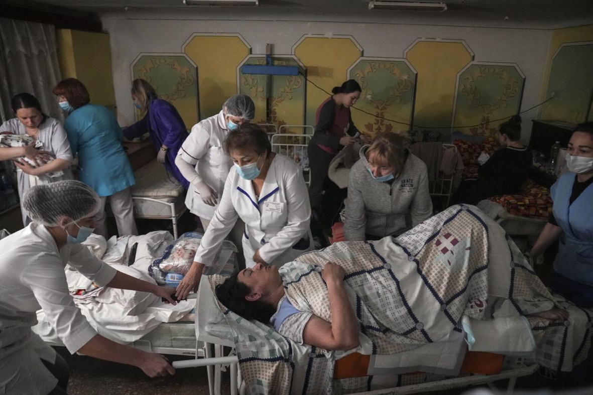 Медичні працівники перевозять пацієнта в підвальному приміщенні пологового будинку, переобладнаному під медичну палату і використовуваному як бомбосховище, Маріуполь, 1 березня